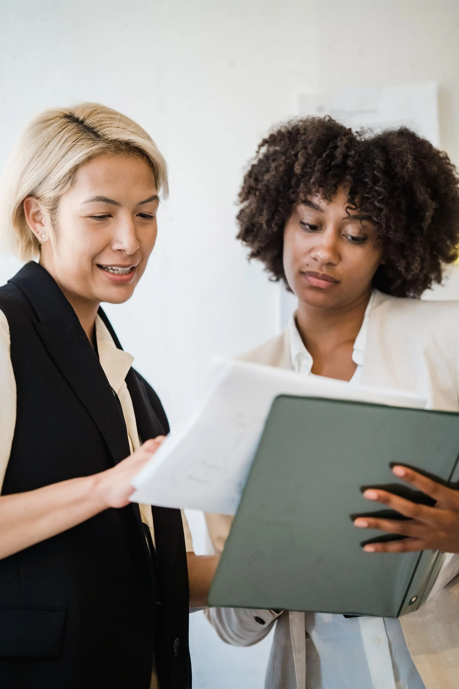 Two professionals reviewing documents in a binder.